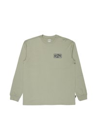 Maglietta a maniche lunghe verde chiaro con colletto a girocollo, caratterizzata da una piccola grafica rettangolare blu navy sul lato sinistro del petto, contenente testo e un logo a onda.