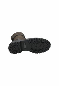 Botte en cuir marron avec une semelle extérieure en caoutchouc noir robuste, dotée de profondeurs et de rainures pour la traction. Détail de boucle au niveau de la cheville.