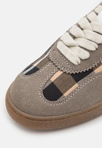 Szare zamszowe sneakersy z wzorzystą tekstylną wstawką w czarne i brązowe paski, kremowymi sznurowadłami oraz teksturowaną gumową podeszwą.