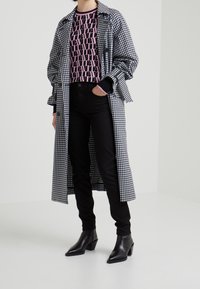 Svartvit gingham-långkappa över en rosa grafisk tröja, svarta slim jeans och svarta klackiga ankelboots. Minimalistisk design, strukturerad passform.