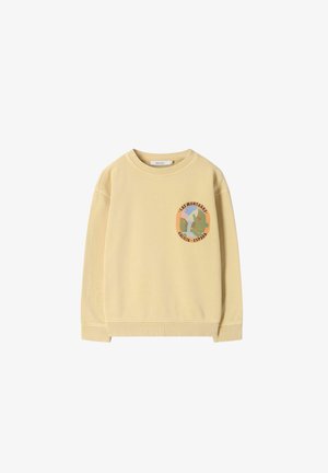 Beige sweatshirt met ronde hals en ronde patch op de borst met abstracte bergen, cactus en de tekst "Las Montañas Galicia España."