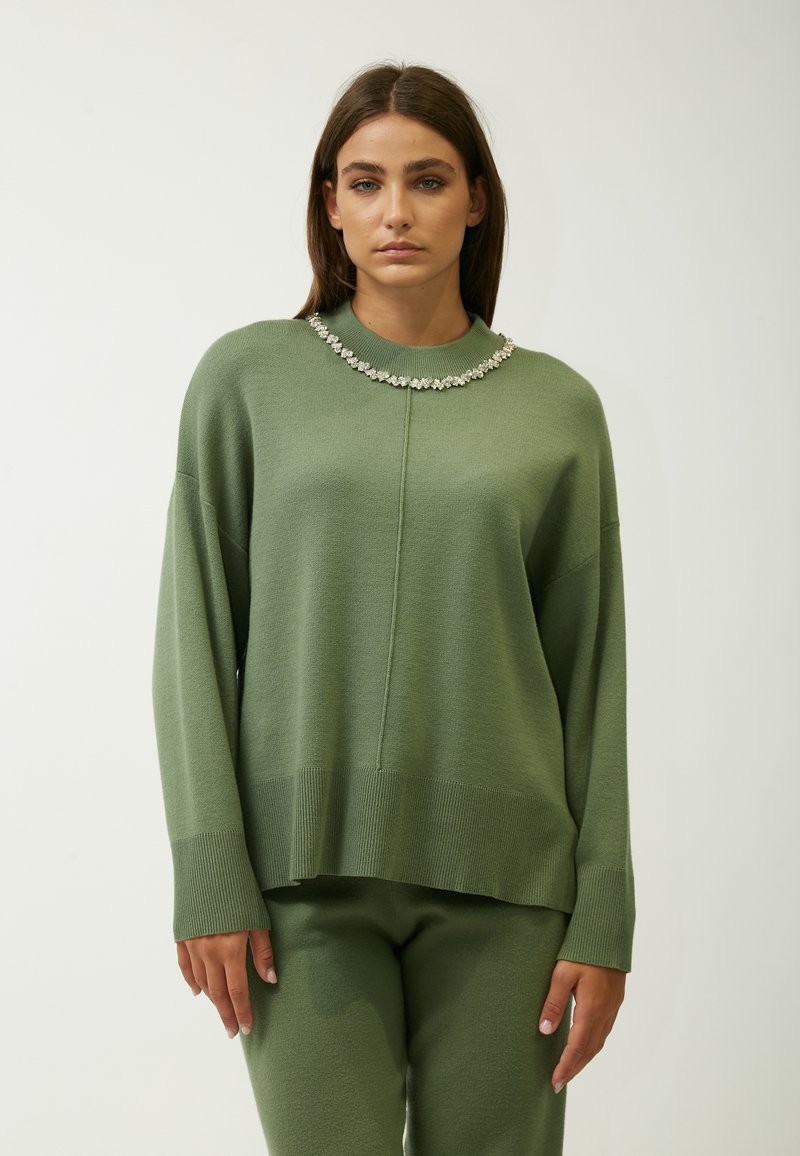 Groene gebreide trui met een hoge hals en een decoratieve kollektion van rhinestones; heeft een losse pasvorm en geribde manchetten, gecombineerd met bijpassende broek.