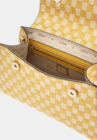 Borse a tracolla gialla con un design a scacchi. L'interno presenta una tasca con zip e il logo del marchio. Chiusura a scatto con dettagli in oro.