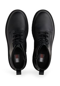 Czarne skórzane botki za kostkę z okrągłymi czubkami, sznurowanym przodem i płaskimi gumowymi podeszwami. Charakteryzują się eleganckim designem oraz brandowaniem Tommy Jeans wewnątrz.