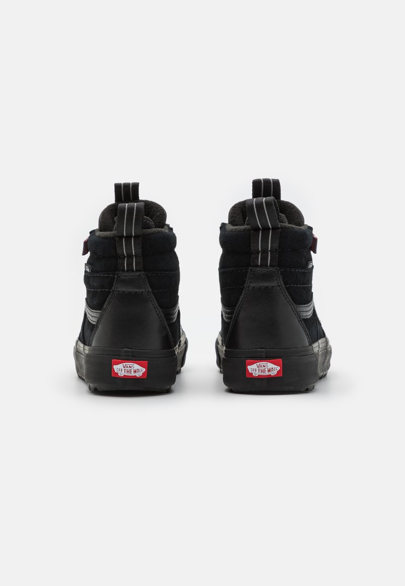 Czarne trampki typu high-top wykonane z zamszu i skóry, z wyściełanym kołnierzem, ciemną gumową podeszwą i czerwoną naszywką Vans z tyłu.