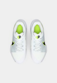 Άσπρα αθλητικά παπούτσια με επάνω μέρος από δίχτυ, γκρι λεπτομέρειες και κίτρινο-πράσινα στοιχεία. Διαθέτουν άσπρα κορδόνια και υφή στη σόλα.