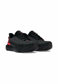 Baskets de sport noires avec une tige en mesh à motif, des accents rouges et une semelle rembourrée. Présente un bout arrondi et des lacets plats.