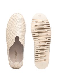 Zapatos beiges sin cordones con una superficie texturizada, similar a la de un reptil. Suela de goma plana con un patrón de banda de rodadura ondulado. Presenta un diseño minimalista y sin hardware visible.