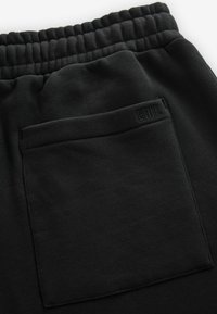 Zwarte joggers van glad katoen met een elastische tailleband en een platte achterzak met stikdetails en een logo.
