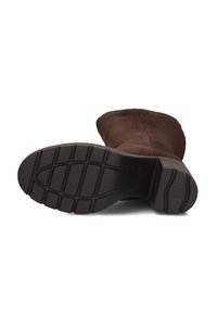 Bruine suède laars met een ronde neus, voorzien van een gestructureerde zwarte rubberen zool met een patroon voor grip.