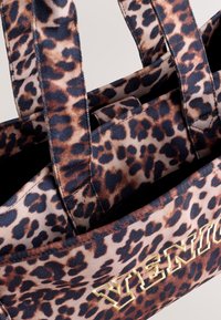 Geantă tote din material textil cu imprimeu leopard, prevăzută cu două mânere rezistente și literă aurie cu inscripția „VENICE”. Modelele variază ca mărime.
