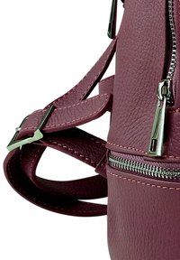 Bordeaux leren handtas met een gestructureerd oppervlak, voorzien van zilverkleurig beslag, verstelbare bandjes en een ritsvak.
