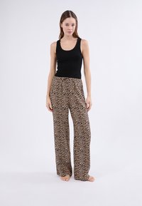 Černá žebrovaná tílko spárované s volnými leopardími kalhotami s drawstring pasem a měkkou, lehkou tkaninou.