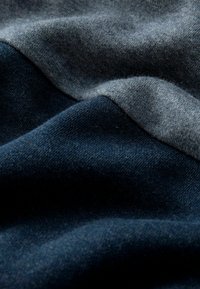 Zacht stof met een mix van donker marineblauw en lichtgrijs, met een gladde textuur en subtiele variaties in schaduw en weving.