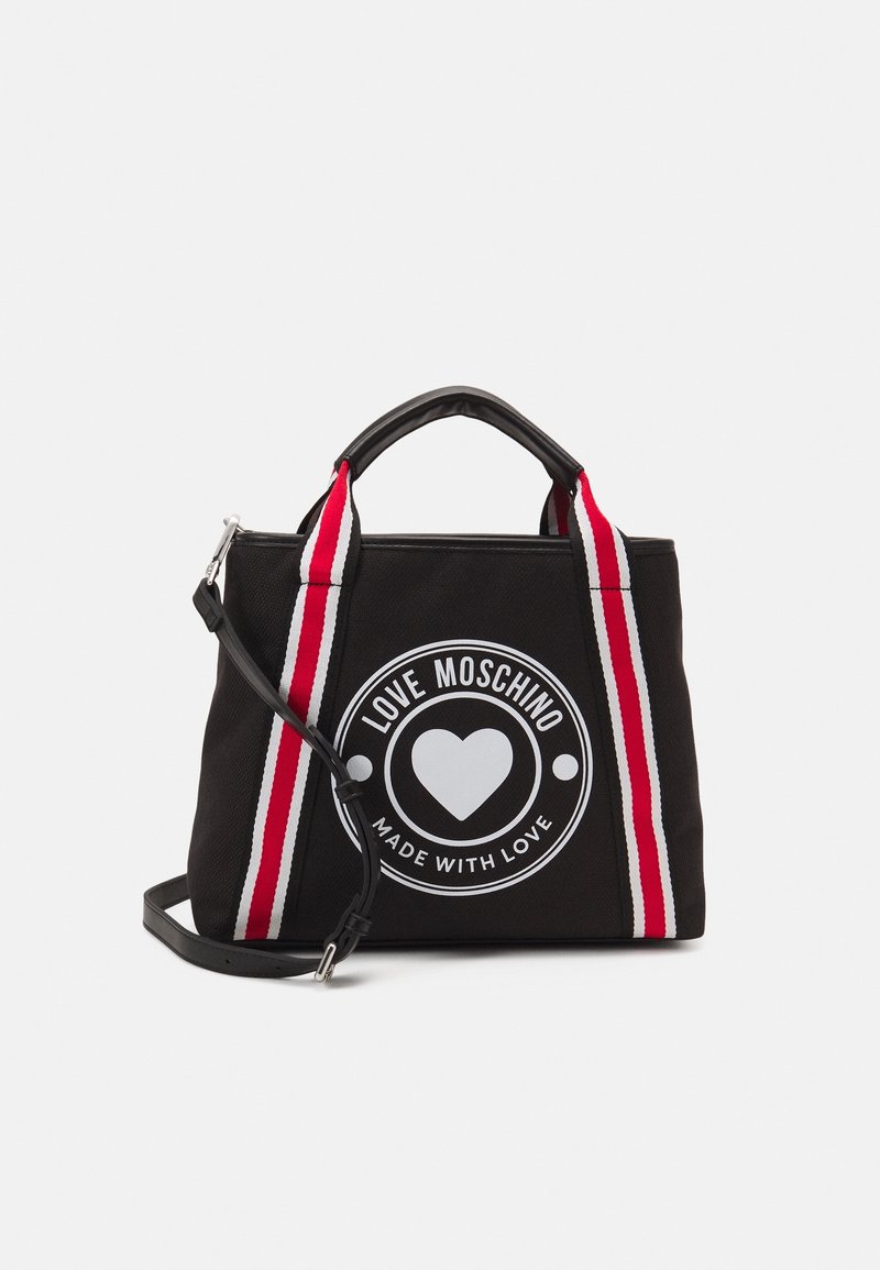 Black canvas bag with a round white logo featuring a heart and text. Red and white striped shoulder straps, short handles, rectangular shape.