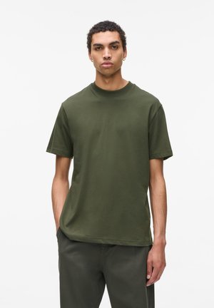 T-shirt en coton olive, à manches courtes, col rond, coupe décontractée, texture lisse, design minimaliste, assortie à un pantalon vert correspondant.
