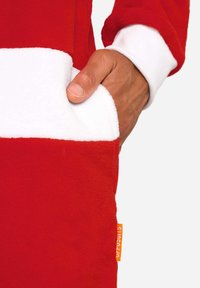 Rood fleece kledingstuk met een brede witte streep, een voorzak en geribbelde witte boorden. Aan de zijkant is een oranje label zichtbaar.