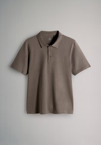 Rjava polo majica iz mehke tkanine z klasičnim ovratnikom, tremi gumbi pri odprtini in kratkimi rokavi. Gladek teksturni videz, brez vzorcev.