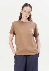 Brown cotton t-shirt with rolled short sleeves, featuring a colorful graphic design on the left chest. Straight cut and soft texture.