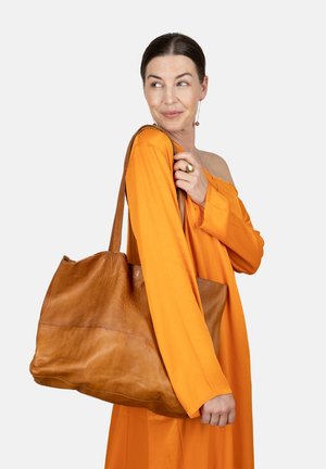 Borsa a spalla in pelle marrone con una texture morbida, forma arrotondata e due manici robusti. Esibita su uno sfondo neutro.