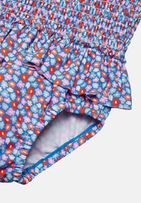 Bañador de una sola pieza con estampado floral, diseño fruncido, volantes en la cintura y fondo azul con flores rojas y rosas. Tejido elástico.