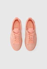 Light pink suede sneakers feature a smooth texture, round toe, and tonal laces, with a rear pull tab and embossed logo on insole.