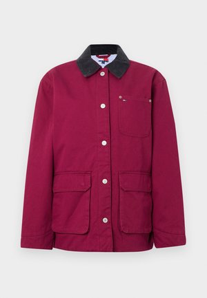 Viininpunainen takki, jossa musta samettinapillinen kaulus, nepparit, kaksi etutaskua ja pieni rintatasku. Kankaan pinta on teksturoitua puuvillaa.