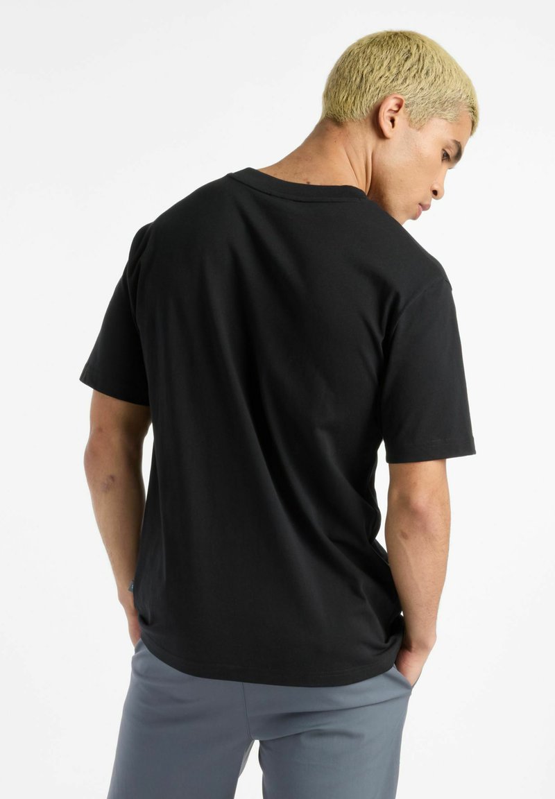 Camiseta de algodón negra con escote redondo y mangas cortas, con un corte relajado y un detalle de costura mínima en el dobladillo.