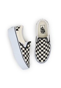 Chaussures à enfiler à motif damier noir et blanc avec une épaisse semelle plateforme blanche, dotées d'une tige en tissu et de surpiqûres contrastantes.