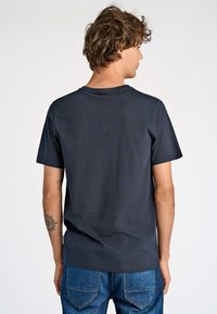T-shirt grigio scuro a maniche corte con scollo rotondo, realizzato in tessuto morbido, mostrato da dietro, abbinato a jeans in denim blu.
