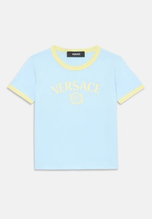 T-shirt de algodão azul claro com mangas curtas. Gola e punhos em amarelo canelado. Apresenta o logótipo "VERSACE" centrado e um gráfico abaixo.