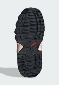 Suela exterior de goma negra con patrón de tracción texturizado, que presenta una etiqueta roja "TRAXION" y detalles lisos. Diseñada para ofrecer tracción y durabilidad.