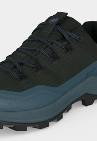 Tumedroheline matkasaabas sinakas-halli tallaga, mustriliste paeltega, Gore-Tex sildiga ja pehmendusega sääreosaga.