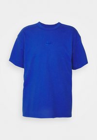 Modrá bavlněná trička s krátkým rukávem, kulatým výstřihem a malým logem Nike ve tmavší modré barvě uprostřed hrudi. Jednoduchý, jednobarevný design.