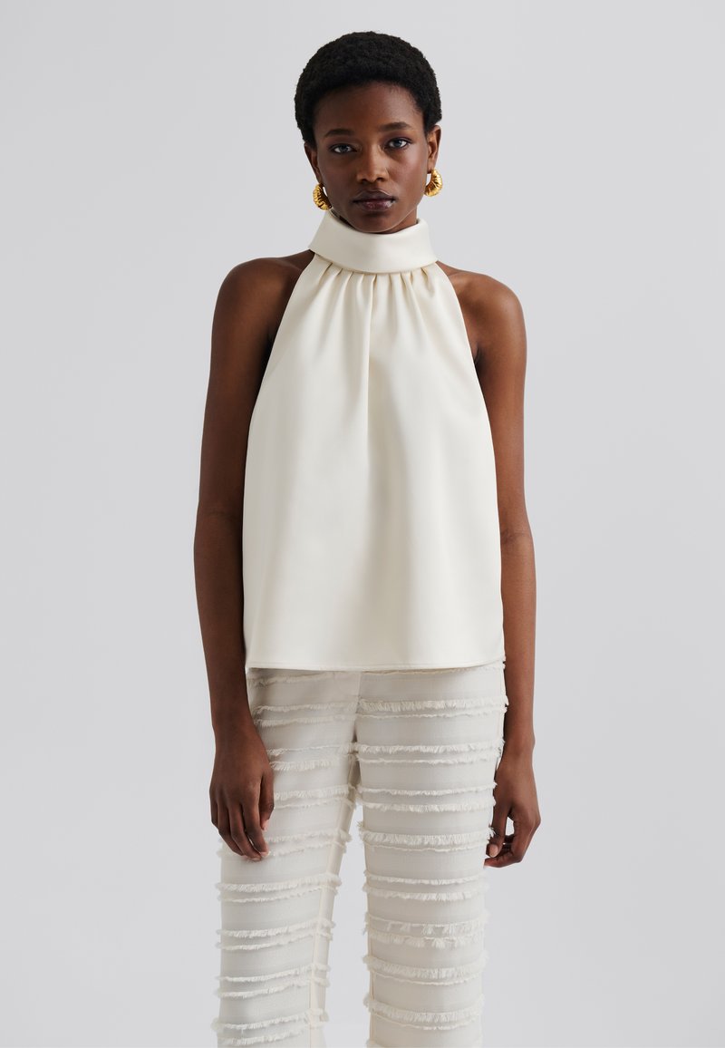Kermansetti halter top kanssa kokoon kerätty kaula-aukko, yhdistettynä kevyisiin, frangoituihin housuihin, joissa on vaakasuorat raidat. Silkkinen kangas.