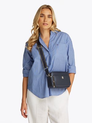 Tengerészkék bőr keresztpántos táska arany színű fémezéssel, téglalap alakú és elegáns dizájnnal. Állítható vállpánt és cipzáras zsebek láthatóak.