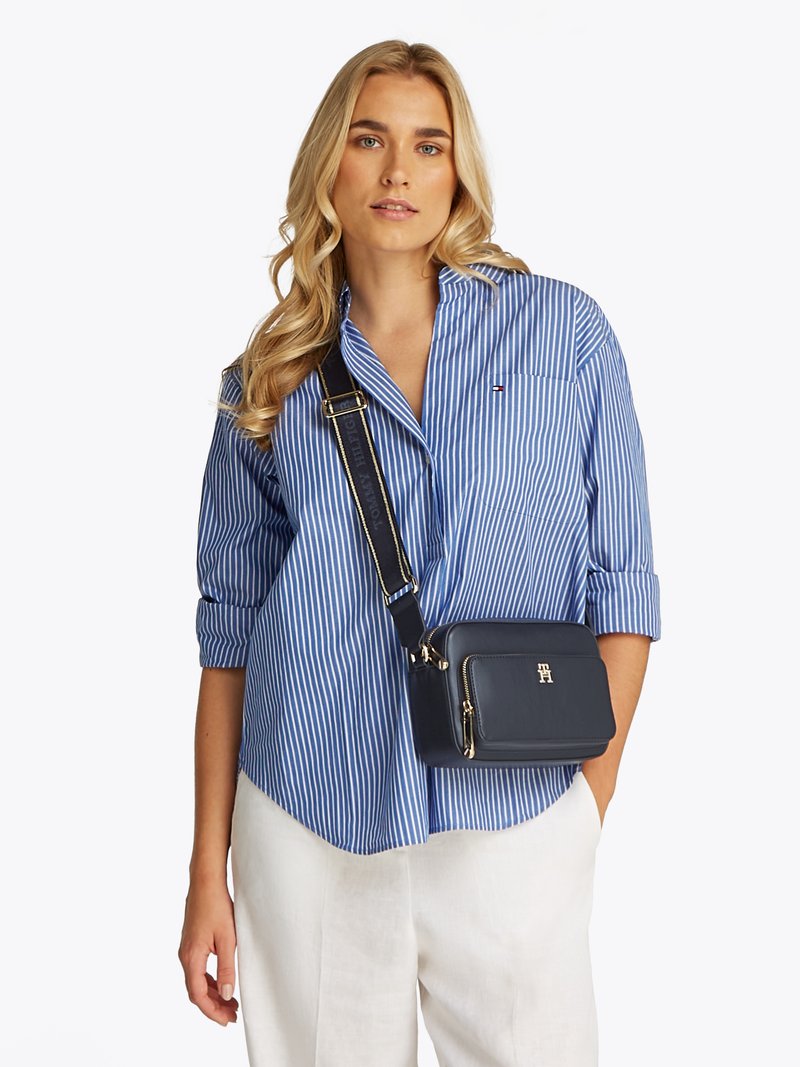Navy leather crossbody bag with gold hardware, rectangular shape, and sleek design. Adjustable strap and zippered compartments visible.