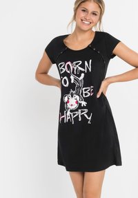 Abito nero a maniche corte con grafica "NATO PER ESSERE FELICE", caratterizzato da una scimmia sorridente in stile cartoon, collo rotondo e dettagli con bottoni a pressione.