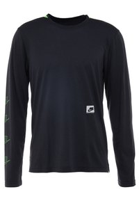 T-shirt noir à manches longues Nike avec petit logo blanc en bas à droite sur le devant et des détails graphiques verts sur la manche gauche et l'épaule.