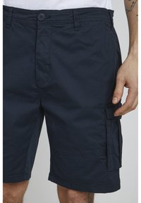 Marina cargo shorts gjorda av bomullsblandat tyg, med sidofickor, knappstängning och en avslappnad passform med en slät yta.