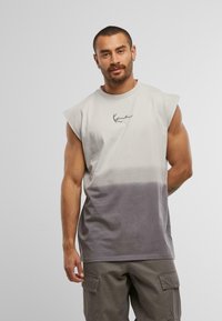Ärmelloses T-Shirt, Farbverlauf von hellgrau zu dunkelgrau, aus Baumwollstoff. Verfügt über ein kleines gesticktes Logo auf der Brust.