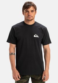 Black cotton t-shirt featuring a small white logo on the left chest. Crew neck, short sleeves, regular fit. Smooth texture.