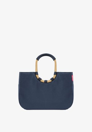 Sac fourre-tout en tissu bleu marine avec une forme structurée, doté d'une poignée circulaire accentuée d'or et de poignées texturées contrastantes sur la poignée.