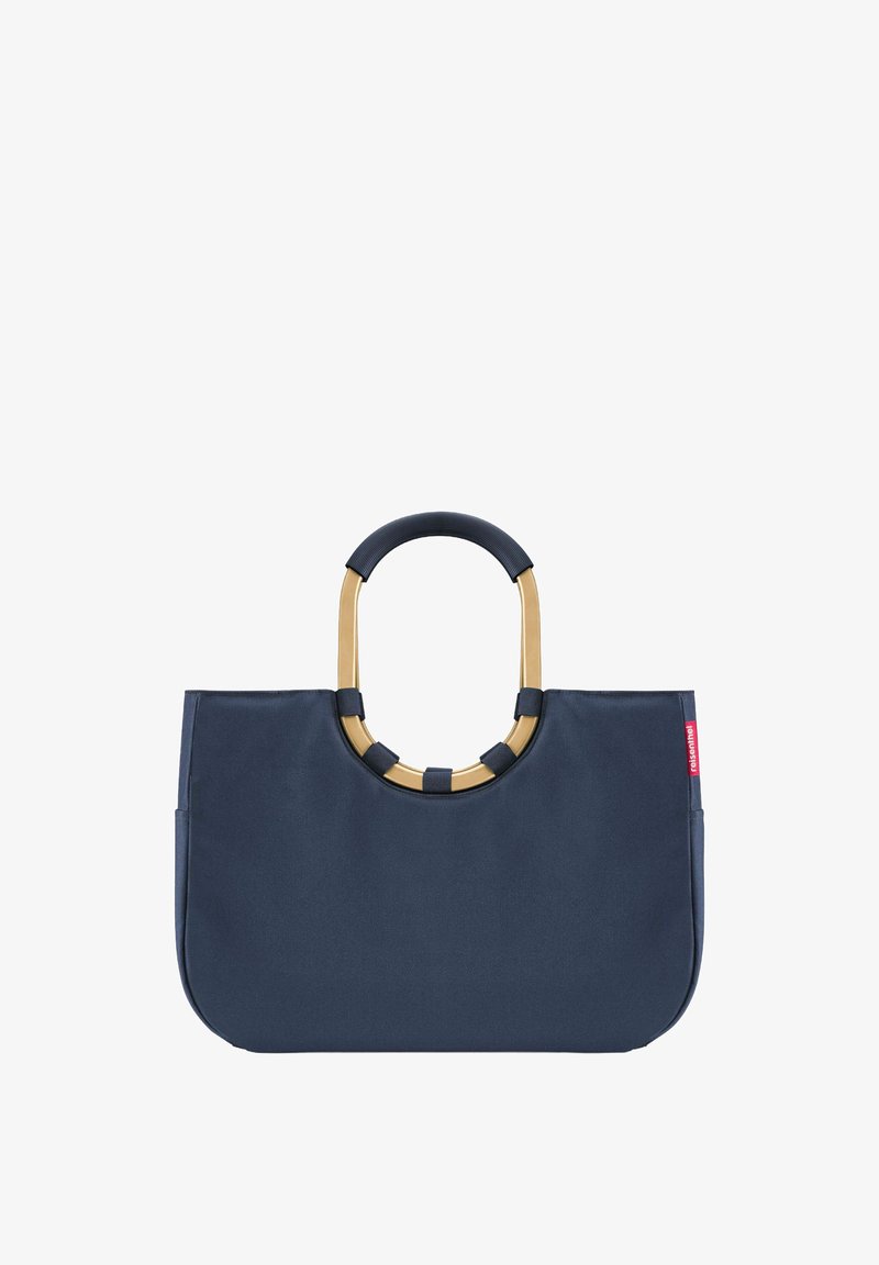 Sac fourre-tout en tissu bleu marine avec une forme structurée, doté d'une poignée circulaire accentuée d'or et de poignées texturées contrastantes sur la poignée.