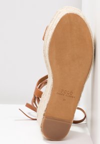 Brun läder espadrille sandal med vävd jutesula, tan fotbädd och justerbara remmar. Märkt med "POLO RALPH LAUREN" på undersidan.