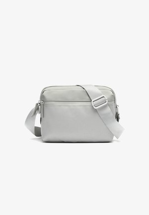 Compact light gray crossbody bag with adjustable strap, front zipper pocket, and smooth fabric upper section.