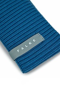 Tessuto a maglia blu a coste con un'etichetta grigia intrecciata che mostra il nome del marchio "FALKE" in lettere bianche.