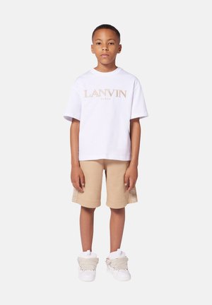 T-shirt en coton blanc avec le logo "LANVIN PARIS" en doré, shorts beiges avec un détail texturé sur le côté, et sneakers blanches avec des accents beiges.
