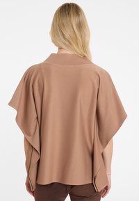 Brown kimono-style cardigan with wide sleeves, soft texture, and a smooth finish. Back view highlights the draping design and collar detail.