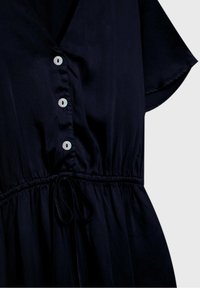 Robe bleu marine foncé à manches courtes, avec quatre boutons blancs sur le devant et une ceinture à lien coulissant à la taille.